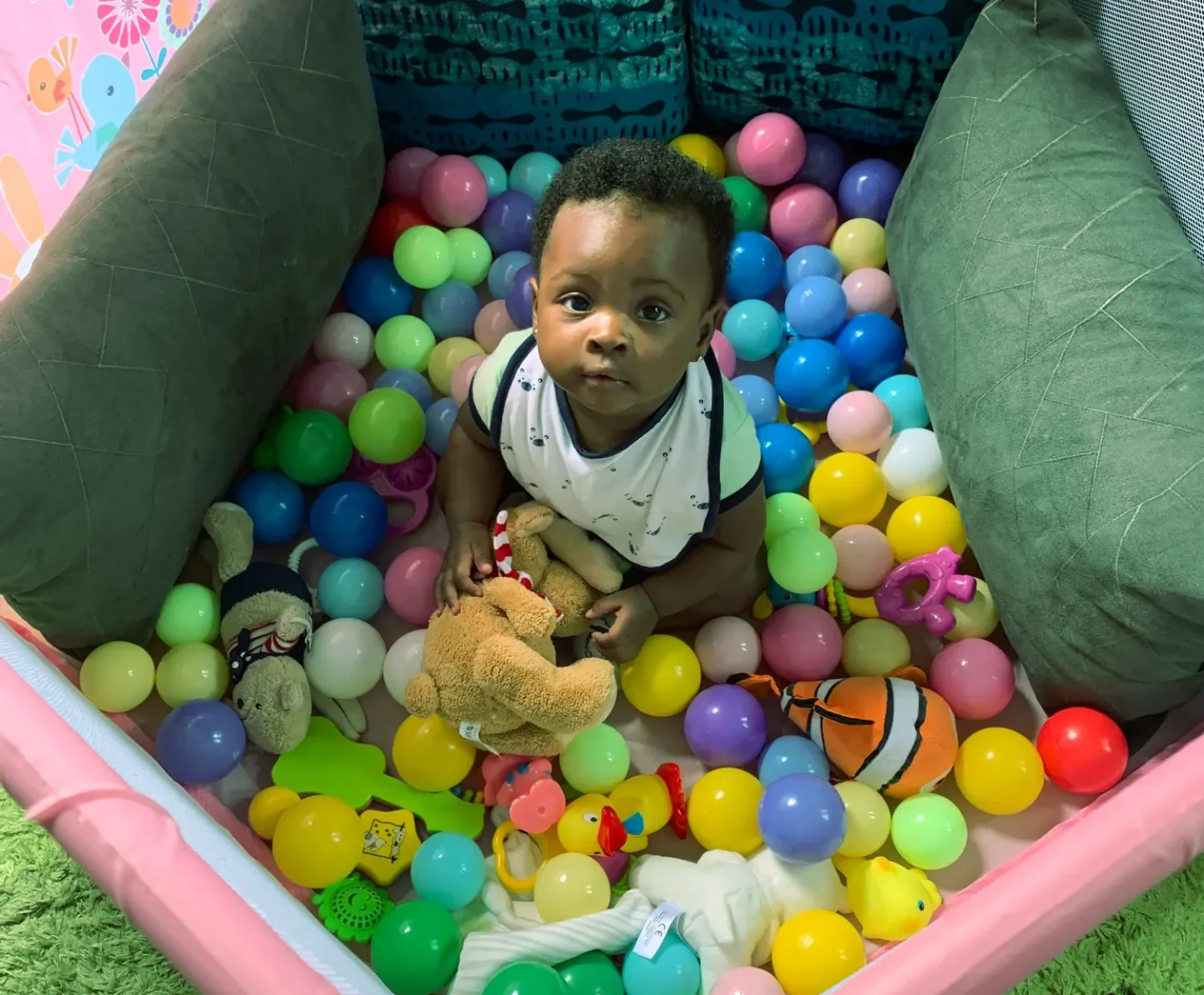 African baby playing in ball pit looking up